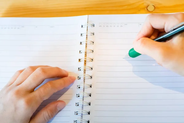 Vrouwelijke hand met potlood schrijven op notebook bij Coffee Shop. vrouw — Stockfoto