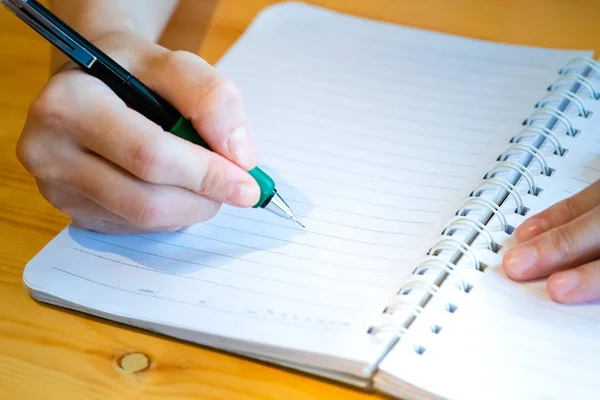 Vrouwelijke hand met potlood schrijven op notebook bij Coffee Shop. vrouw — Stockfoto