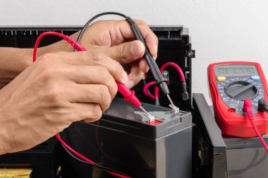 Pil voltajı Ups (kesintisiz güç kaynağı) multimetre ile ölçüm teknisyeni.