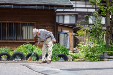 Gifu, Japonya - 16 Mayıs 2016: Shirakawa-go yolda temizlik bir tanımlanamayan Japon ihtiyar. Shirakawa-go (Shirakawa köyü) Dünya Miras köyüdür.