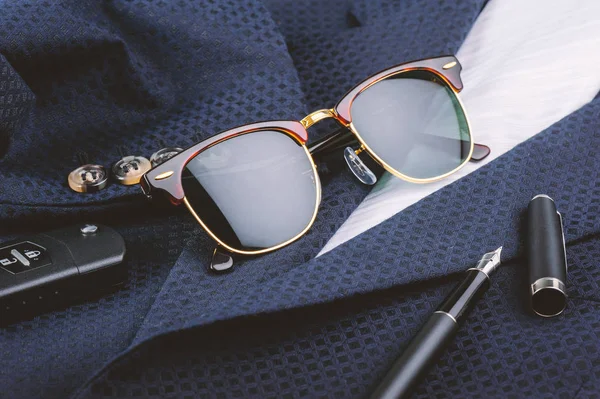 accessories, closeup sunglasses with gold frame on navy blue suit