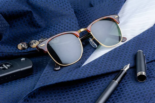 accessories, closeup sunglasses with gold frame on navy blue suit