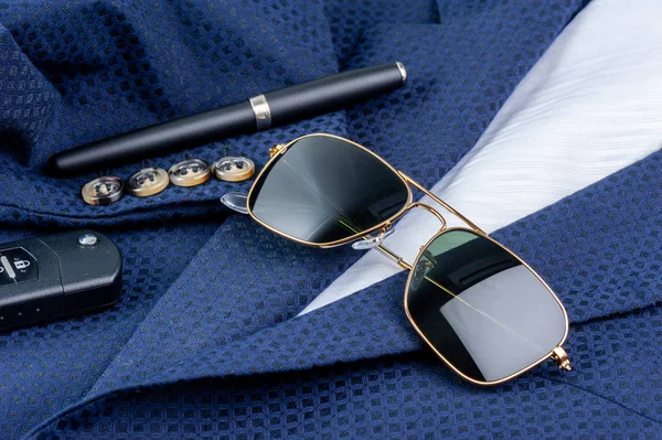 accessories, closeup sunglasses with gold frame on navy blue suit