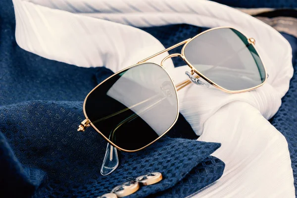 accessories, closeup sunglasses with gold frame on navy blue suit