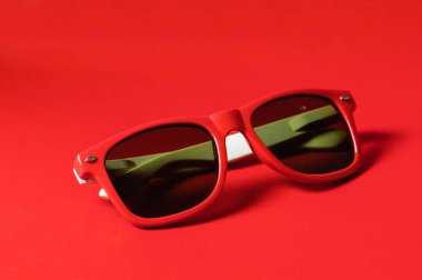 Kadın aksesuar, kırmızı arka planda kırmızı plastik gözlük.