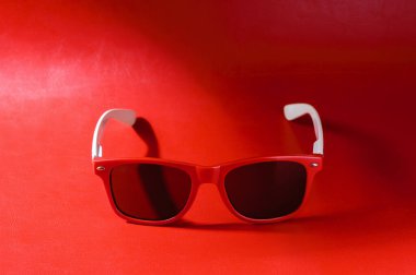 Kadın aksesuar, kırmızı arka planda kırmızı plastik gözlük.