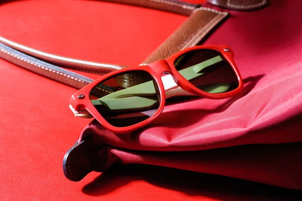 女性用アクセサリー赤い背景の上に閉じたプラスチックのサングラス — ストック写真