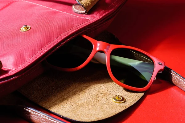 woman accessory, closeup red plastic sunglasses over red background