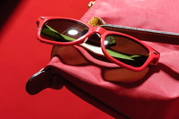 woman accessory, closeup red plastic sunglasses over red background