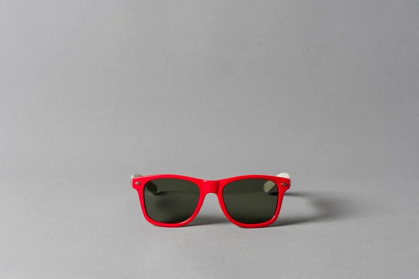 woman accessory, closeup red plastic sunglasses isolated over gray background