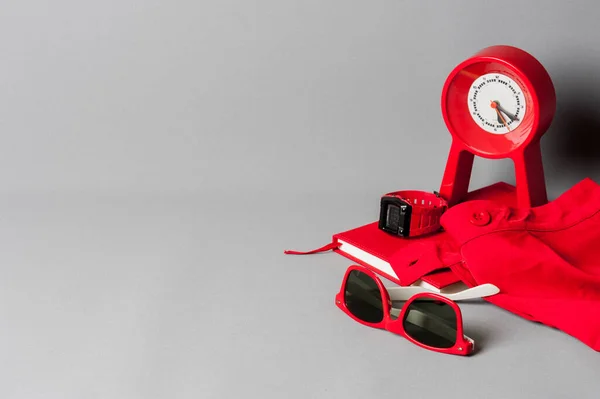 red objects, sunglasses, notebook, clock, watch, closeup at red plastic sunglasses
