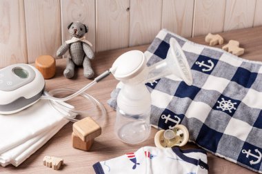 Göğüs pompası ve tahta arka planda boş bir bebek şişesi.