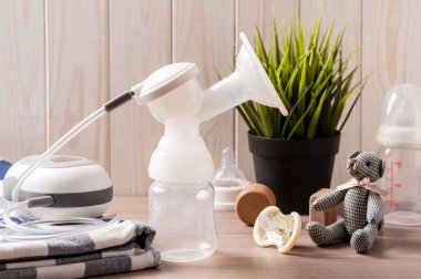 Göğüs pompası ve tahta arka planda boş bir bebek şişesi.