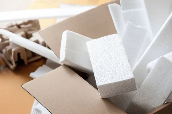 Closeup white polystyrene foam in parcel box. Polystyrene foam is cushioning material in packaging, material for craft applications and other.