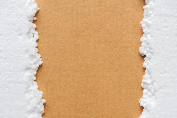 Closeup white polystyrene foam on the cardboard. Polystyrene foam is cushioning material in packaging, material for craft applications and other.