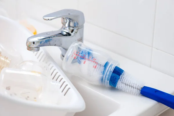 washing baby bottles and nipples with soft bottle brush and dishwashing liquid