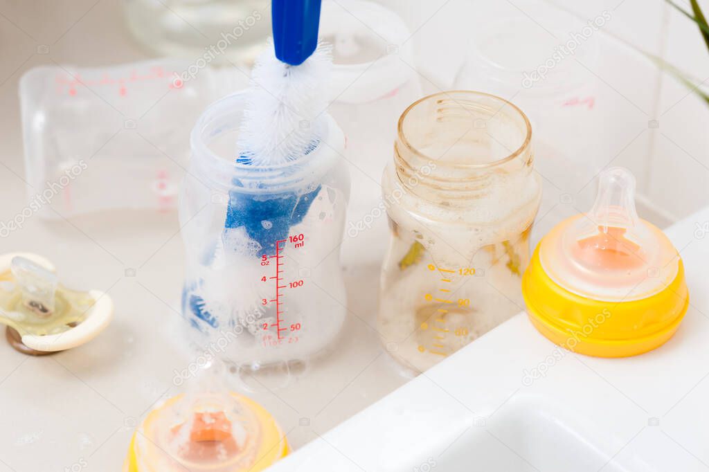 washing baby bottles and nipples with soft bottle brush and dishwashing liquid