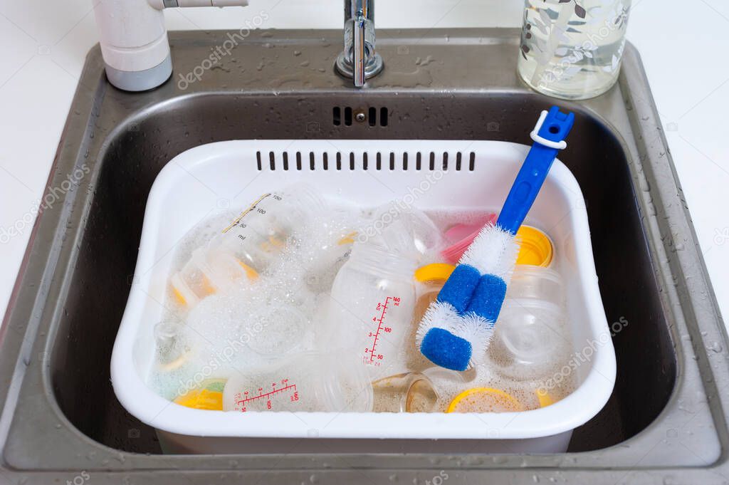 washing baby bottles and nipples with soft bottle brush and dishwashing liquid