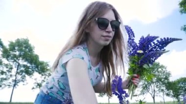 Güzel kız çayırda lupines alır. Çiçek lupins bir buket ile Kız.