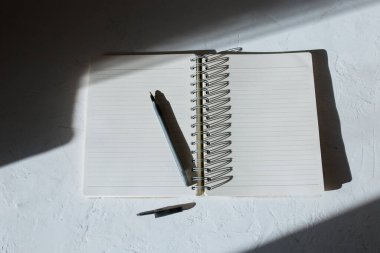 beyaz arkaplanda gölgeli kalemli defter