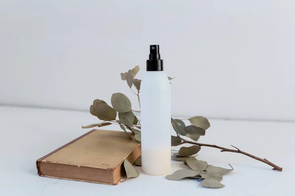 dry eucalyptus in a vase with a book, cosmetic, containers for cosmetics