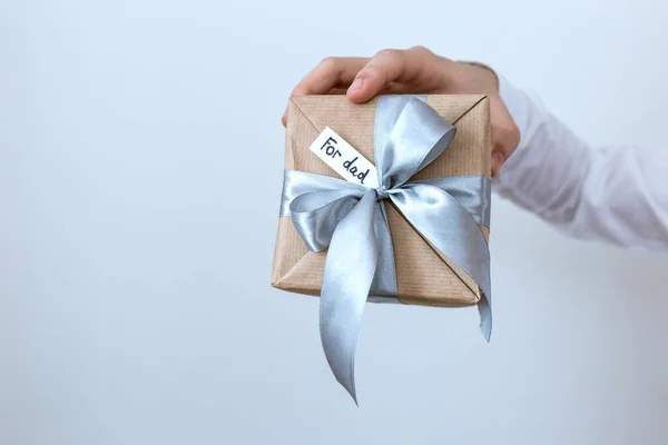 a gift in craft packaging in the hands of Father\'s Day, give, a gift for the holiday