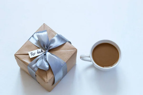 gift in craft packaging with a cup of coffee on the table for Father's Day, give, a gift for the holiday