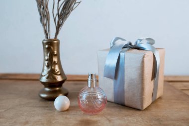 Parfüm pembe bir şişede Tahta bir masada hediye kutusuyla