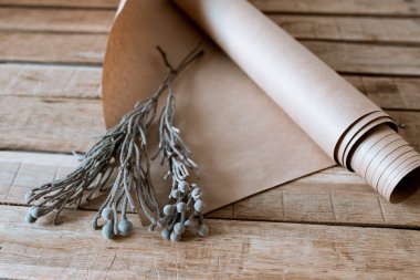 Gümüş bir fiyonk, ahşap bir masa üzerinde kağıt ve çiçekli bir hediye.