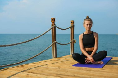 kadın sahil spor kıyafeti üzerinde oturuyor