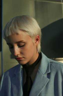 ciddi üzgün genç kadının portre yakın yukarı bakarak, kısa beyaz saç, mavi ceket, siyah kravat, açık havada