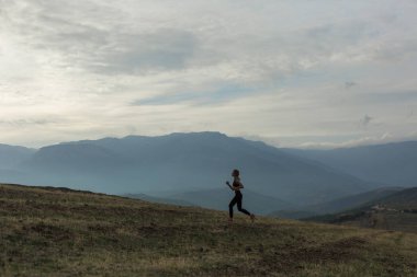 İnce kız silüeti sisli dağda koşu