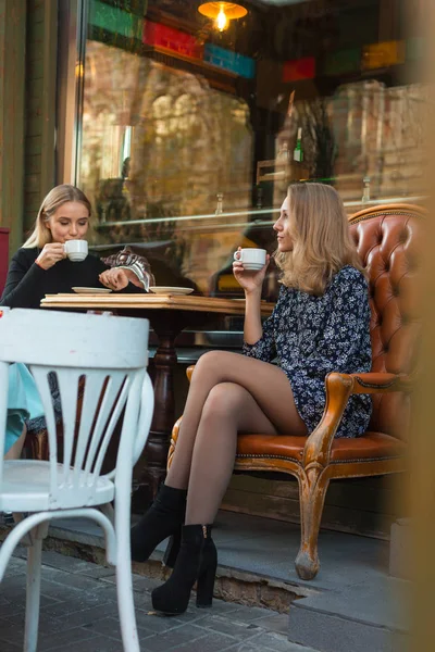 Girlfriends are drinking coffee outdoors