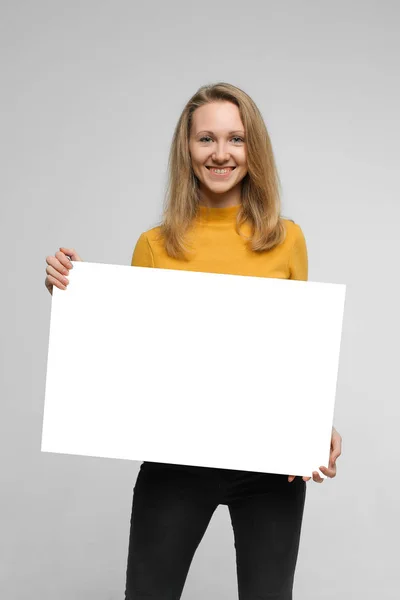 Smiling young woman with poster — Stock Photo, Image