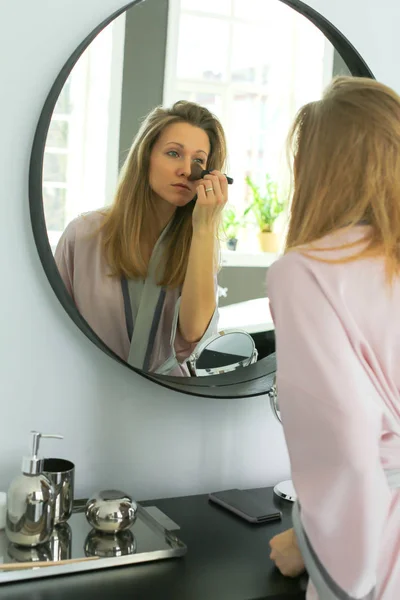 Bonita mujer está aplicando maquillaje — Foto de Stock