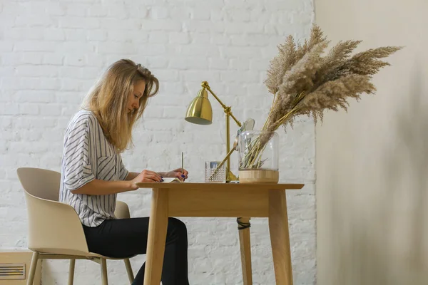 woman is handwriting at the table