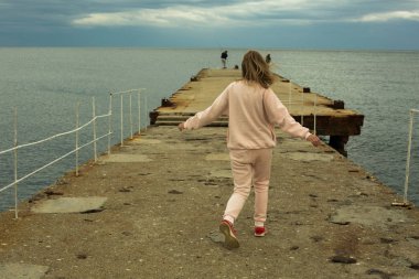 Kadın sahilde iskelede koşuyor.