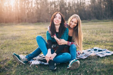 Gün batımında çimlere oturup iki genç erkek. En iyi dostlar