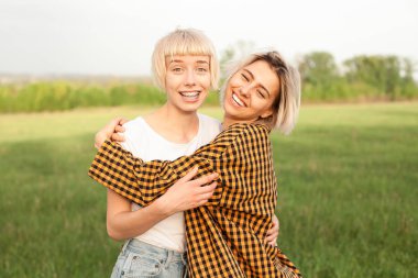 İki genç kadın sarılma ve açık havada eğleniyor. En iyi dostlar