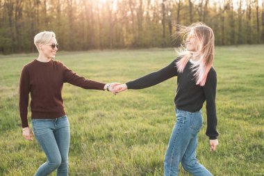 İki kadın güneş ışığı altında sahada yürüyor.