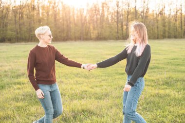 İki genç kadın güneş ışığı altında sahada yürüyor. En iyi dostlar