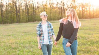 İki genç kadın sahada günbatımında yürüyüş