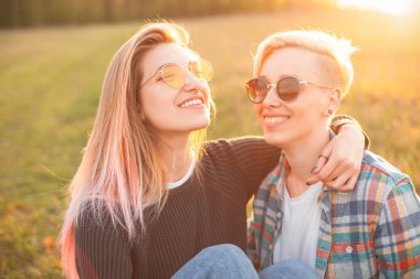 Gün batımında çimlere oturup iki genç erkek.