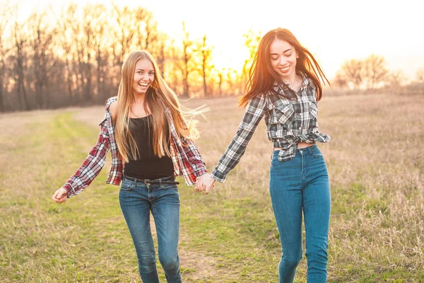 两位年轻女子在夕阳下的绿地里玩得开心 最好的朋友 — 图库照片