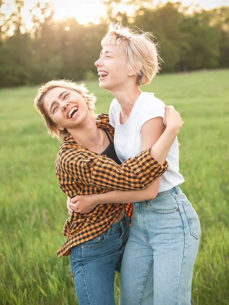 Two young women laughing and hugging outdoors. Best friends