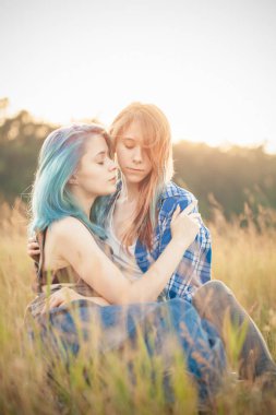 Gün batımında çimlere oturup iki güzel genç kadın.