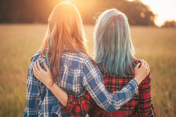 Two girls standing on the background of sunset. Best friends