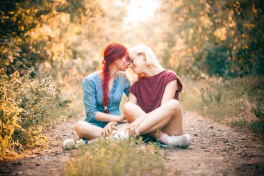 Orman yolu üzerinde oturan iki genç kadın.