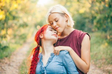 Orman yolu üzerinde oturan iki genç kadın. En iyi dostlar