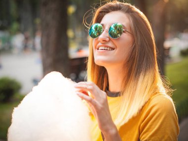 Pamuk şeker Parkı ile günbatımında poz genç gülümseyen kadın